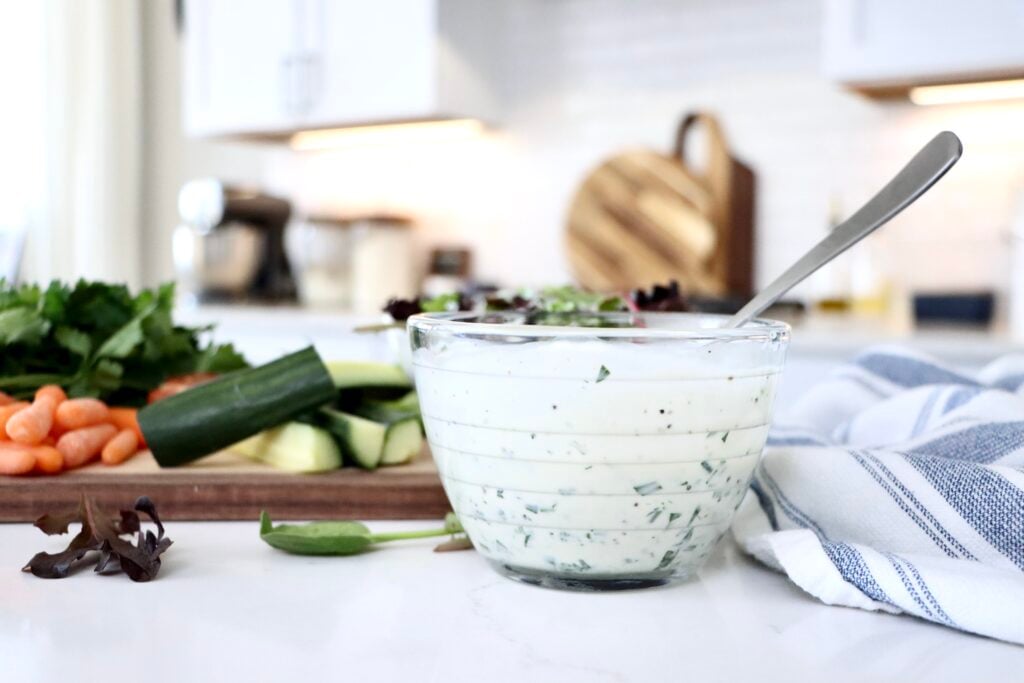Creamy homemade ranch dressing in a small glass bowl with fresh herbs