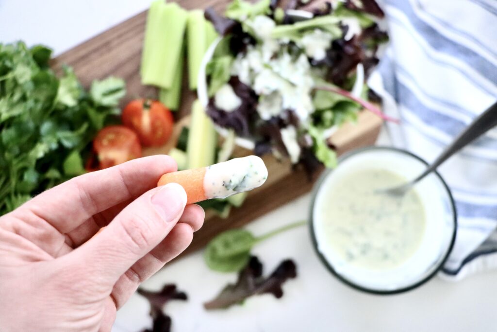 Homemade ranch dressing next to a tray of raw vegetables for dipping