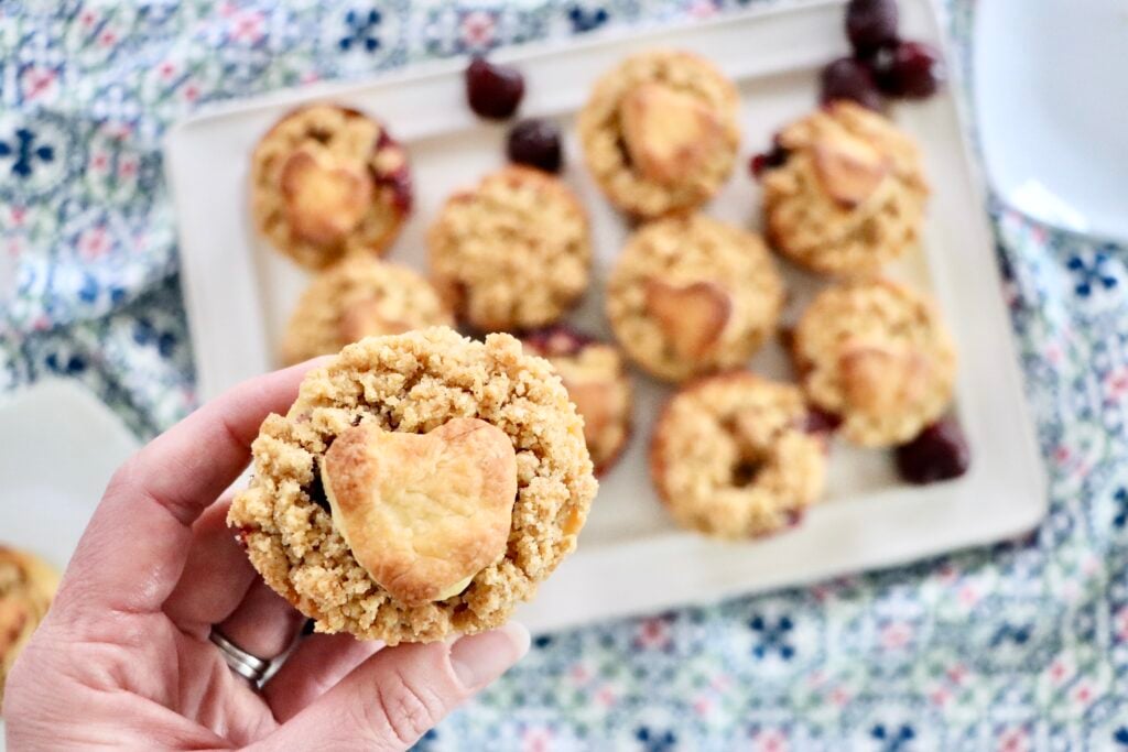 Handheld mini cherry pies with buttery streusel topping, fresh cherries bubbling inside.