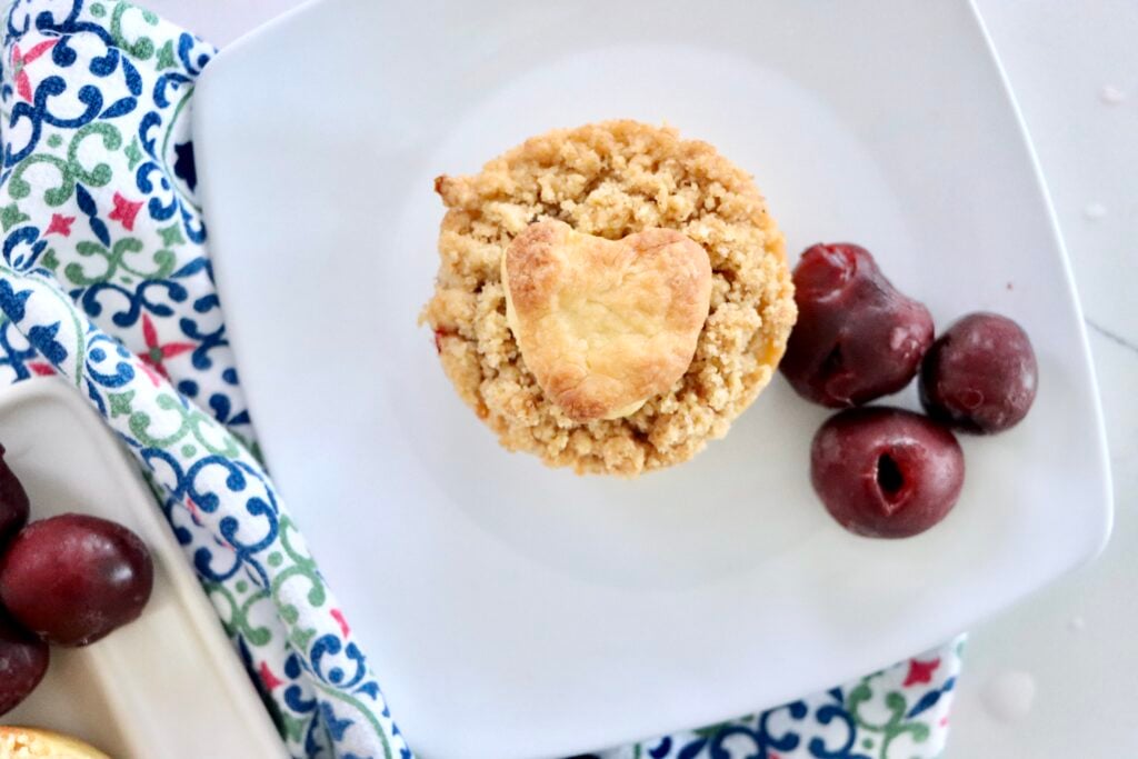 Handheld mini cherry pies with buttery streusel topping, fresh cherries bubbling inside.