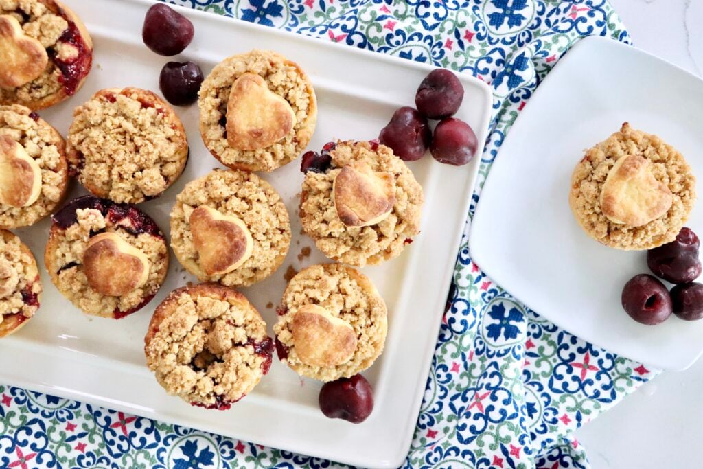 Handheld mini cherry pies with buttery streusel topping, fresh cherries bubbling inside.