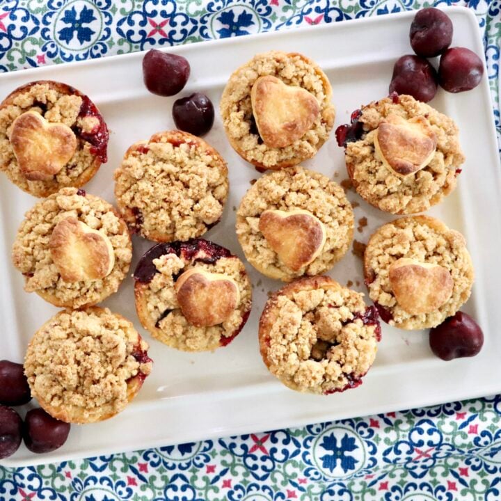 Handheld mini cherry pies with buttery streusel topping, fresh cherries bubbling inside.