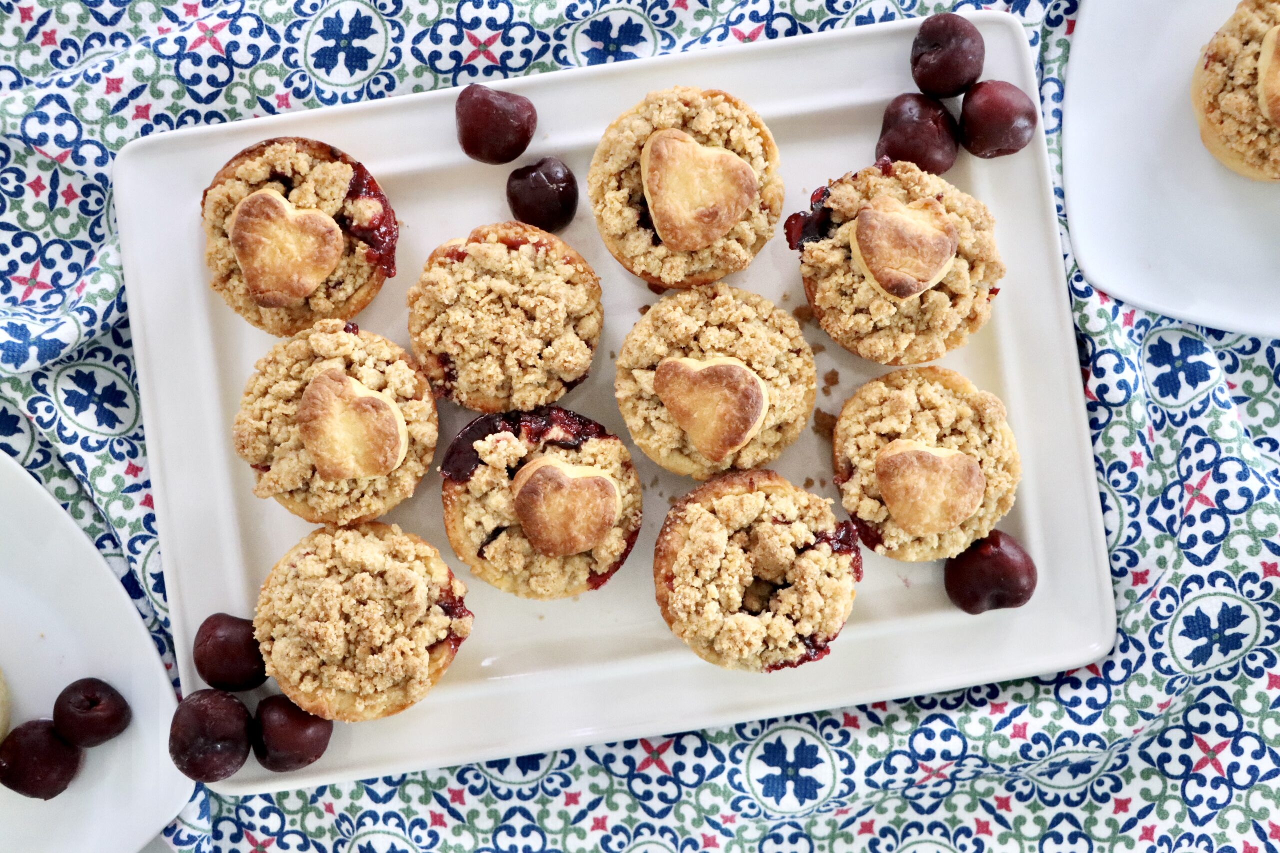 Handheld mini cherry pies with buttery streusel topping, fresh cherries bubbling inside.