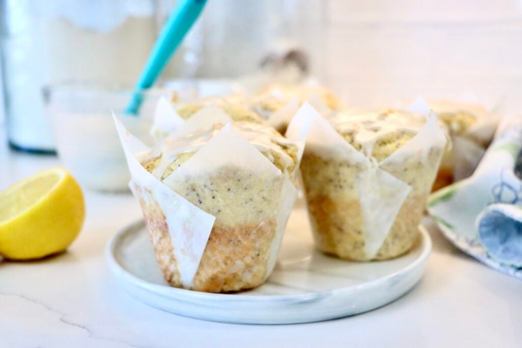 Fluffy sourdough lemon poppy seed muffins with tall bakery style tops and lemon icing