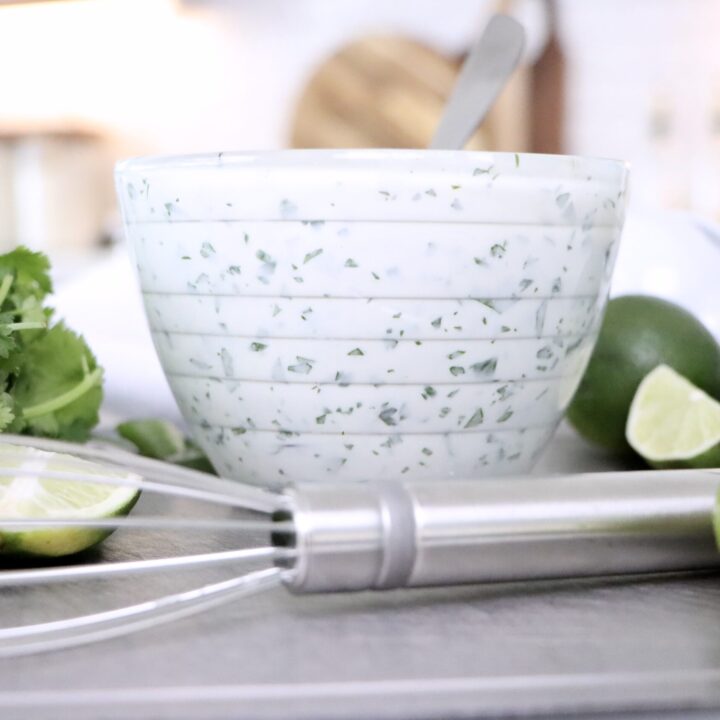Fresh cilantro lime crema in a white bowl, vibrant green flecks of cilantro visible, perfect easy 5-minute taco sauce recipe.