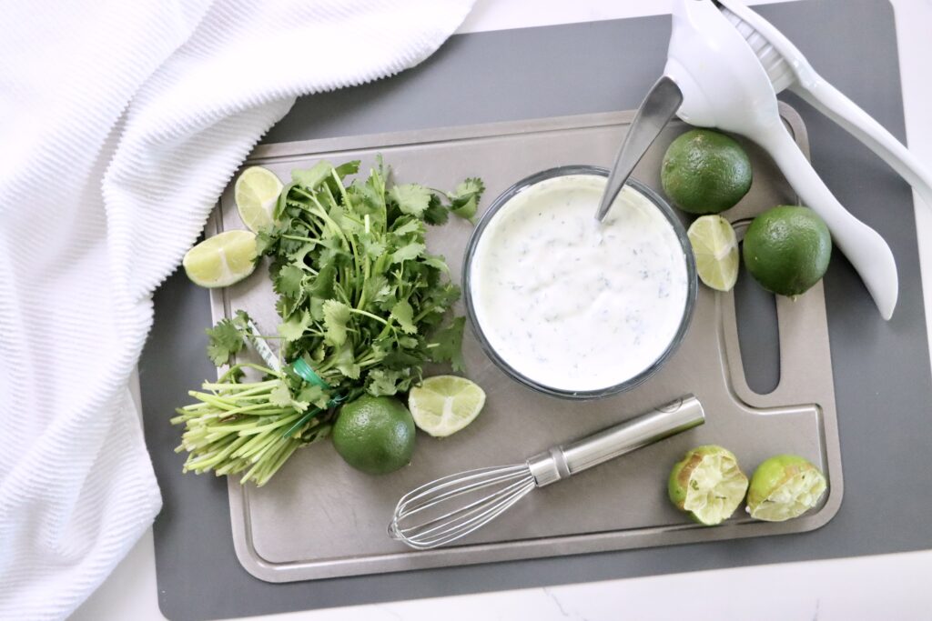 Healthy cilantro lime crema sauce drizzled over tacos, made with Greek yogurt for a lighter, protein-rich alternative to sour cream.