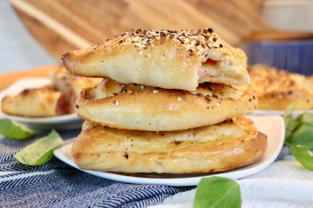 From-scratch ham and cheese hot pockets made with sourdough dough, served warm and golden brown on a plate.