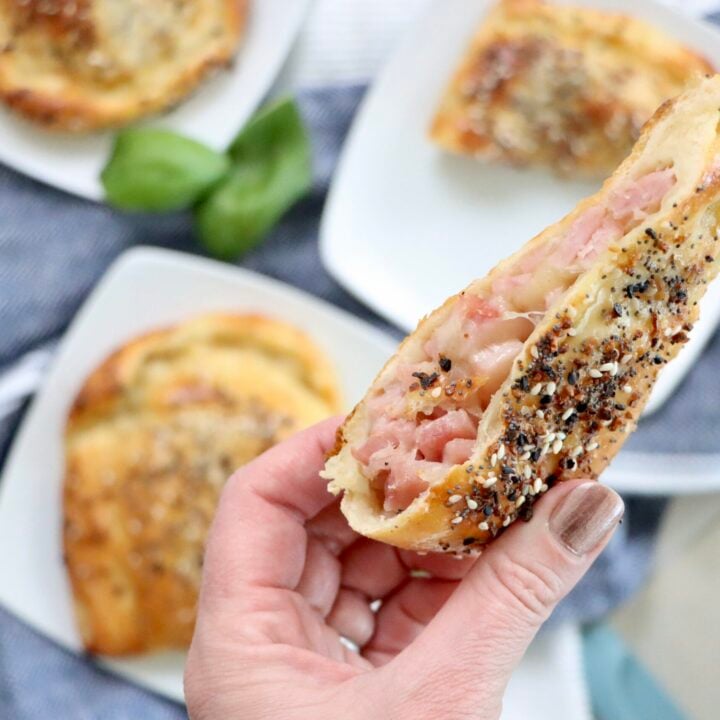 Freshly baked ham and cheese hot pockets cut open showing gooey melted cheddar and diced Canadian bacon filling.