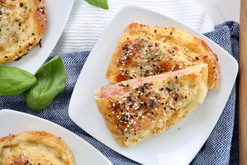 From-scratch ham and cheese hot pockets made with sourdough dough, served warm and golden brown on a plate.