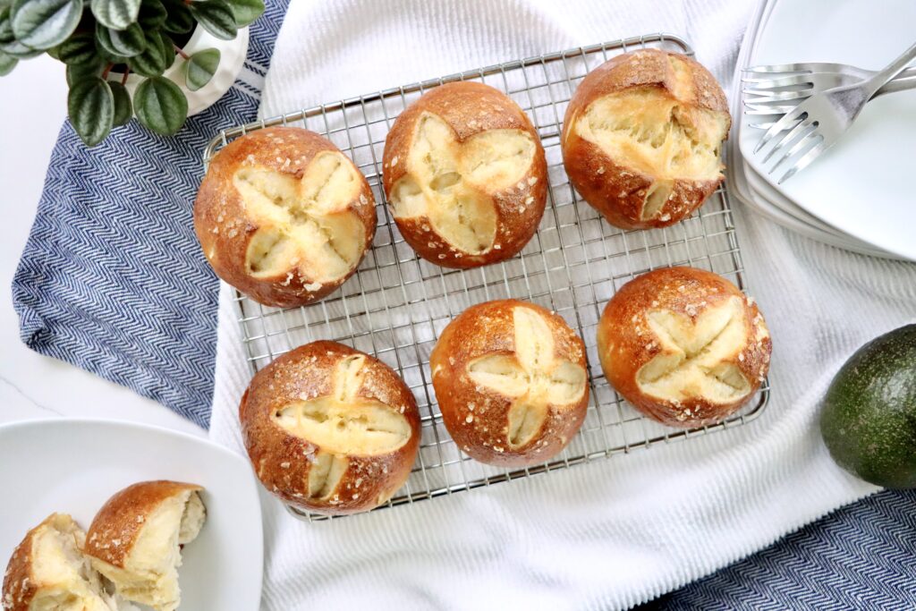 Soft and chewy sourdough pretzel buns with a golden brown crust and flaky salt on top