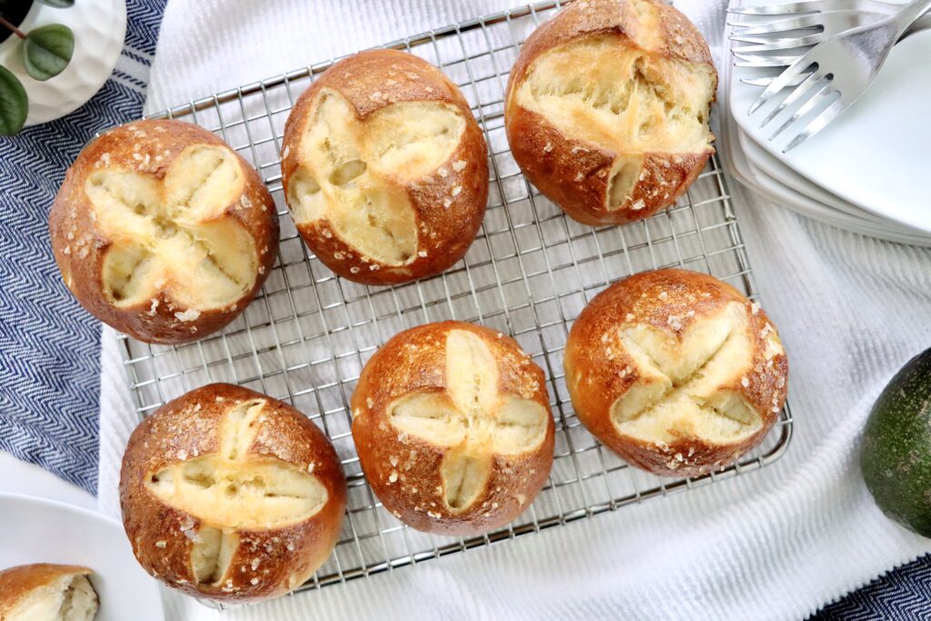 Homemade sourdough pretzel buns brushed with butter and sprinkled with flaky sea salt