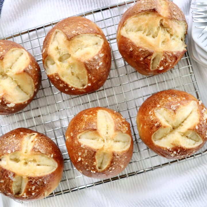 Homemade sourdough pretzel buns brushed with butter and sprinkled with flaky sea salt