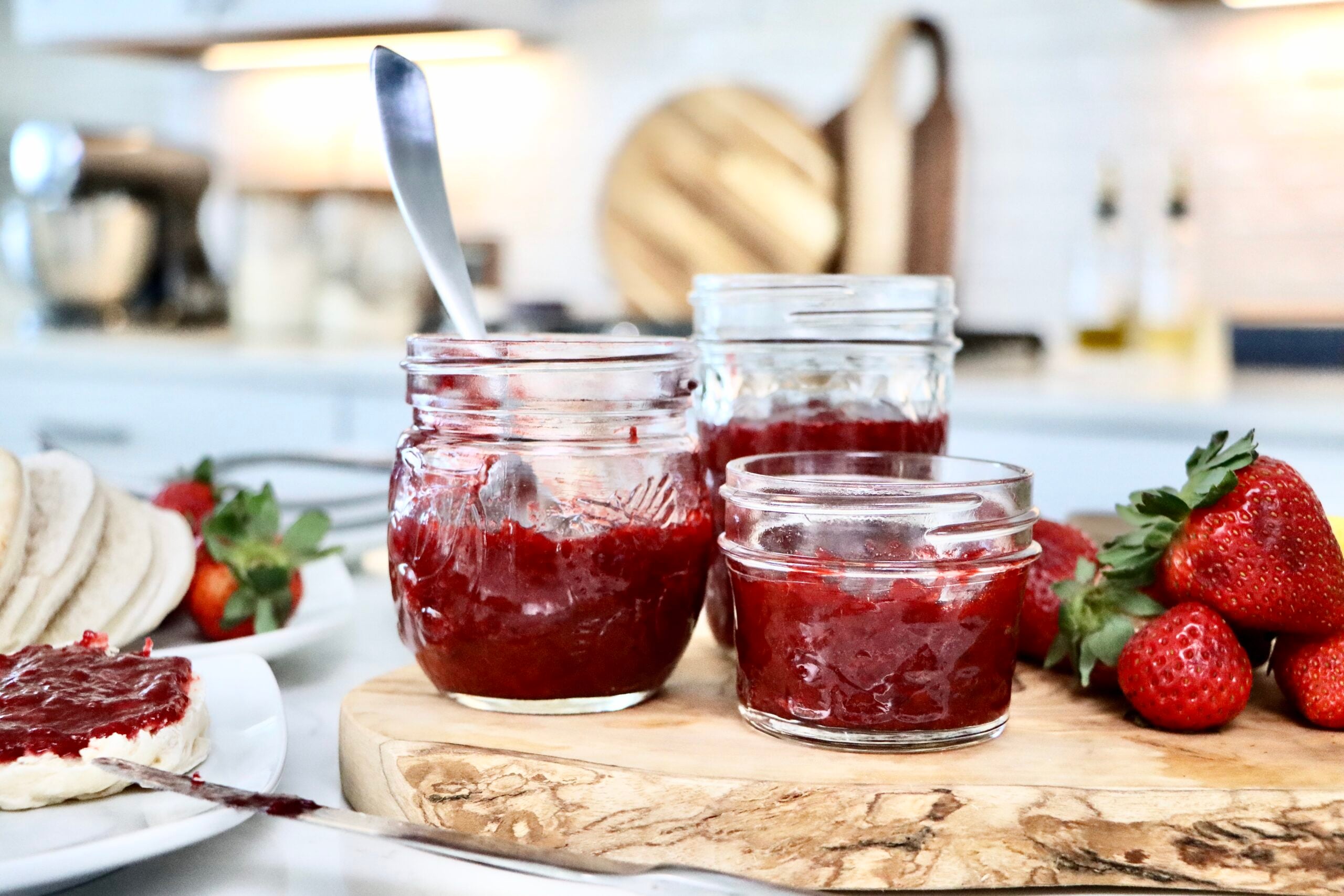Low sugar homemade strawberry jam in a glass jar with fresh strawberries on the side