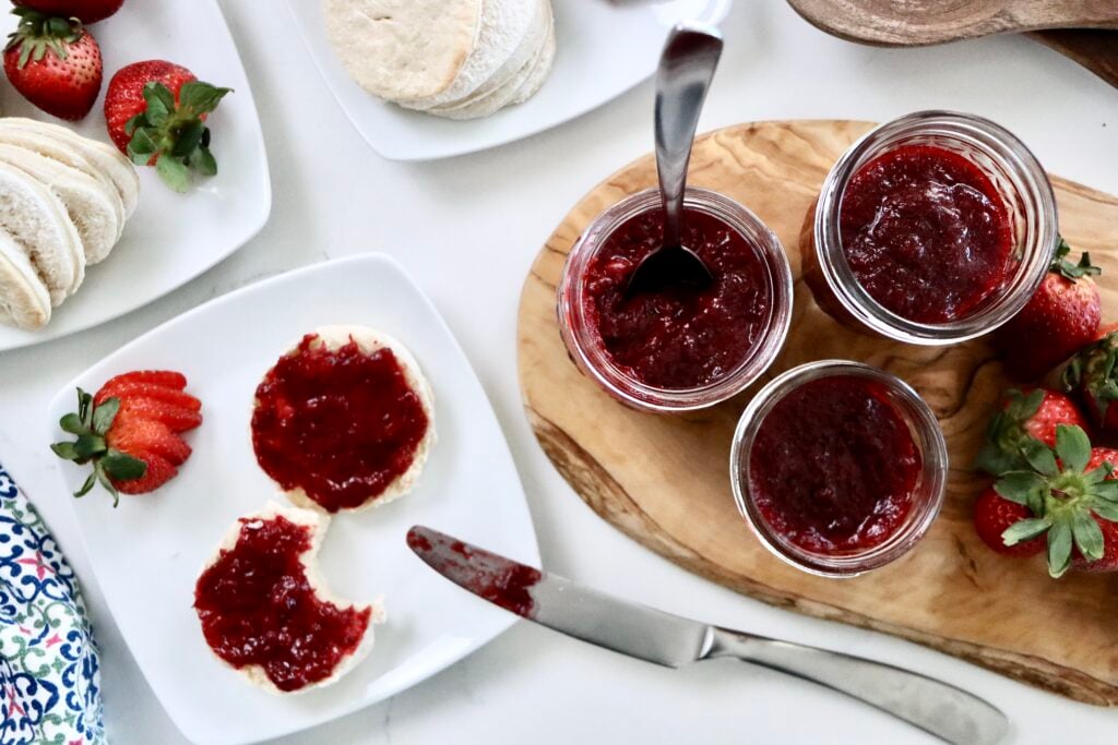 Homemade strawberry jam on a biscuit with visible chunks of fresh strawberries