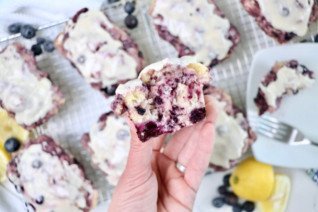 Homemade lemon blueberry bread loaf sliced to show moist crumb and bursts of blueberries inside.