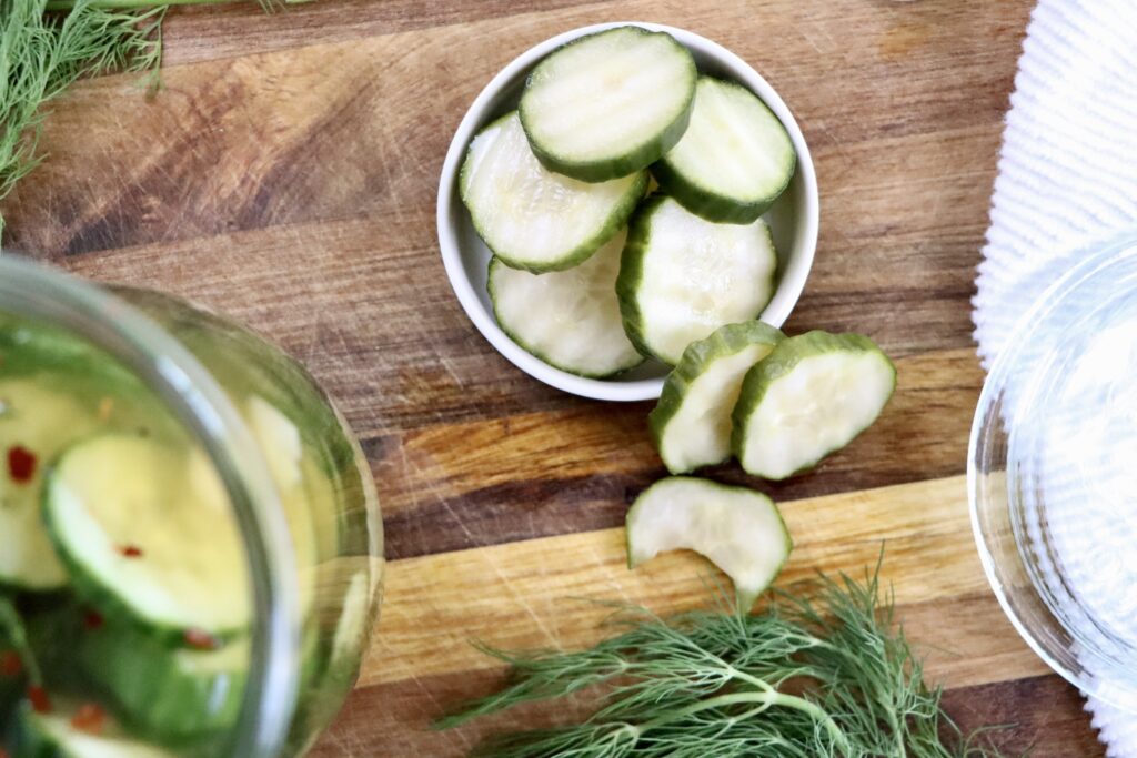 Homemade refrigerator dill pickles in a glass jar with fresh cucumbers, garlic, and dill in a vinegar brine.