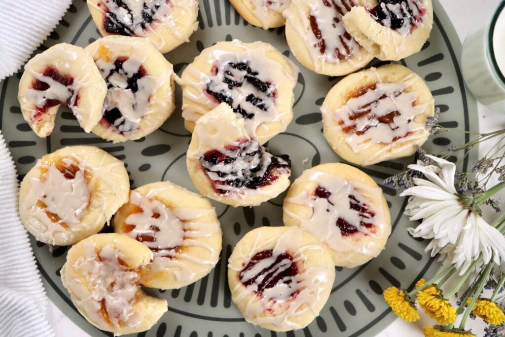 Soft homemade Czech kolaches filled with fruit jam and topped with vanilla glaze on a baking tray