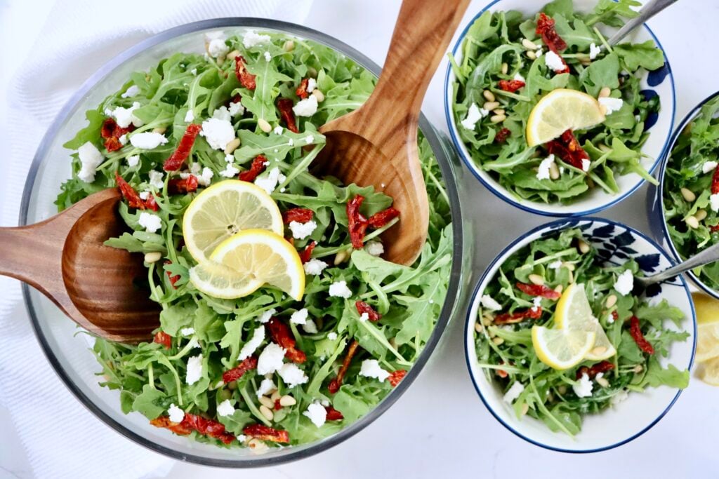 Fresh arugula salad topped with sundried tomatoes, pine nuts, and crumbled goat cheese for a quick healthy meal.