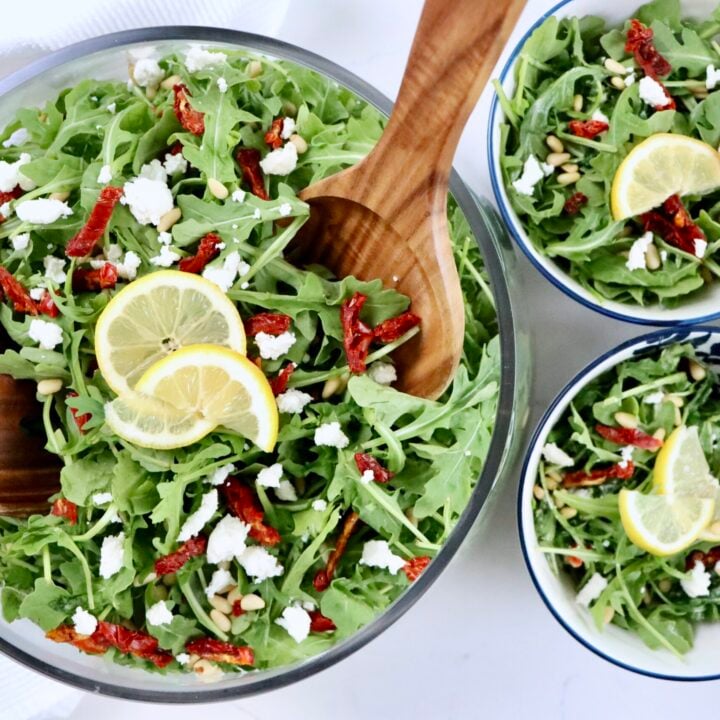 Fresh arugula salad topped with sundried tomatoes, pine nuts, and crumbled goat cheese for a quick healthy meal.