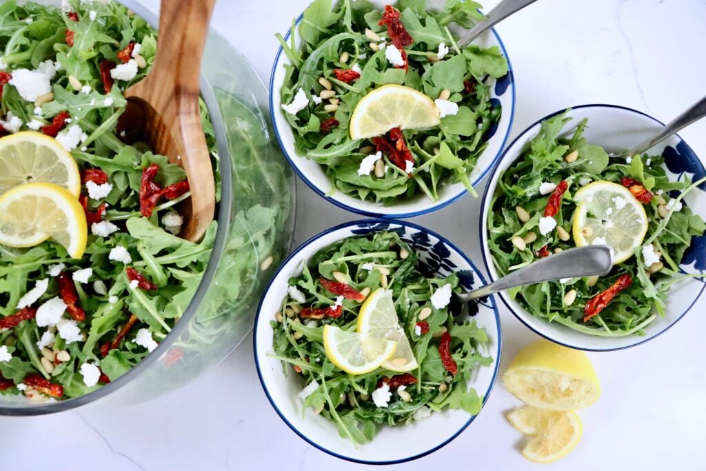 A light and healthy lemon arugula salad served as a fresh side dish with goat cheese and sundried tomatoes.