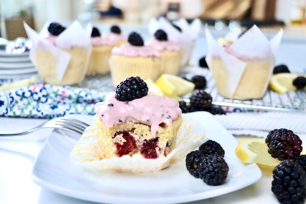 Moist lemon cupcakes filled with fresh blackberries and topped with pink blackberry frosting.