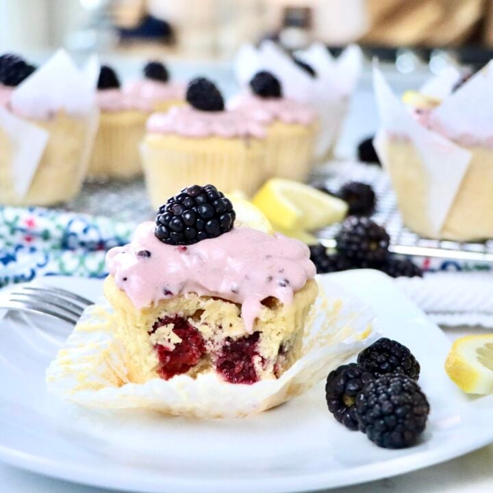 Moist lemon cupcakes filled with fresh blackberries and topped with pink blackberry frosting.