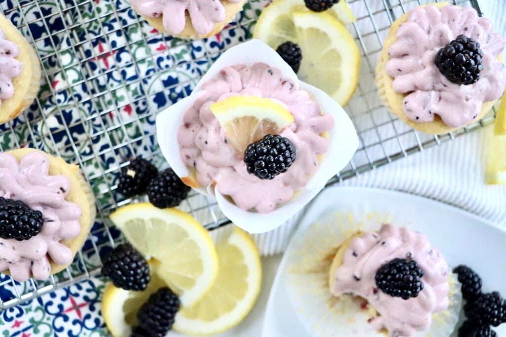 Close-up of lemon cupcakes topped with creamy blackberry frosting and fresh berries.