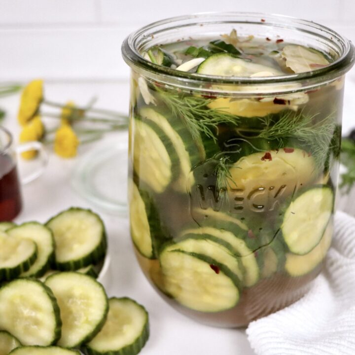 Homemade refrigerator sweet pickles packed in a mason jar with visible cucumbers, garlic, and herbs.