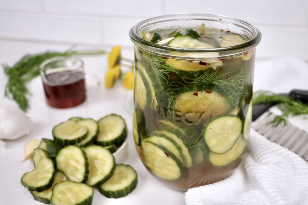 Jar of homemade sweet refrigerator pickles made with cucumbers, fresh dill, garlic, and a maple honey vinegar brine.