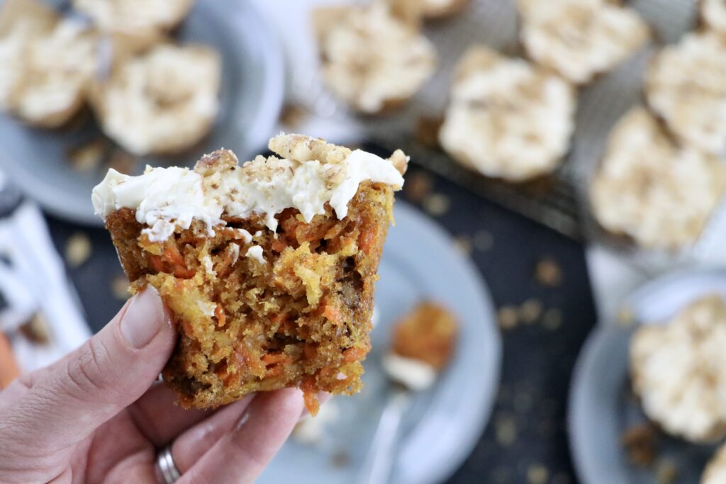 Carrot cake cupcake showing moist interior filled with carrots, pineapple, coconut, and walnuts