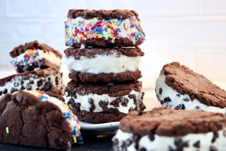Homemade chewy chocolate cookie ice cream sandwiches stacked with creamy vanilla ice cream and rolled in mini chocolate chips
