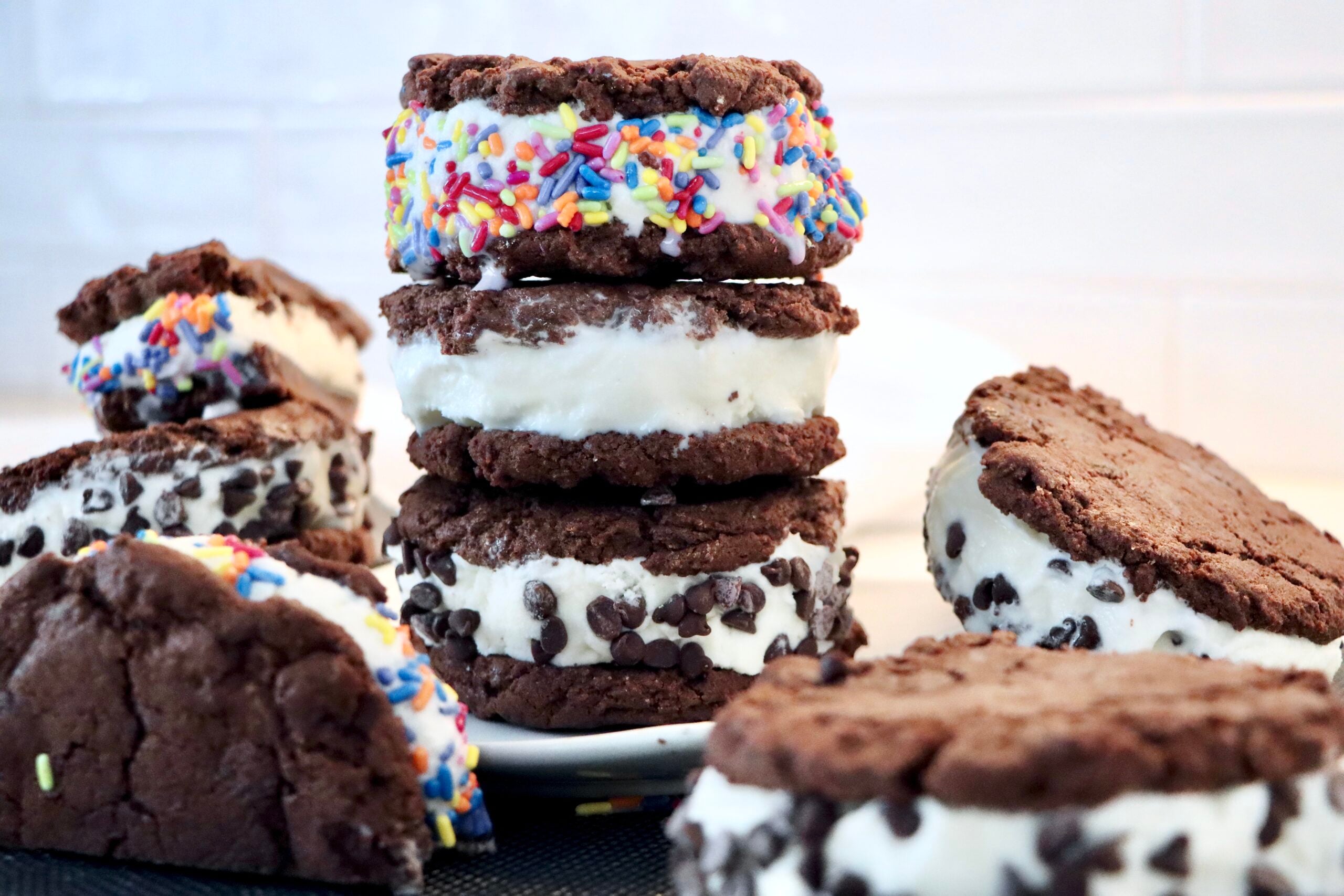 Homemade chewy chocolate cookie ice cream sandwiches stacked with creamy vanilla ice cream and rolled in mini chocolate chips