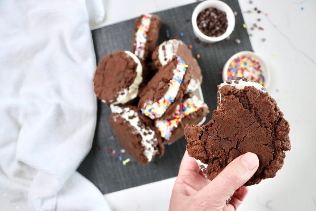 Close up of bitten chocolate cookie ice cream sandwich showing creamy vanilla ice cream center