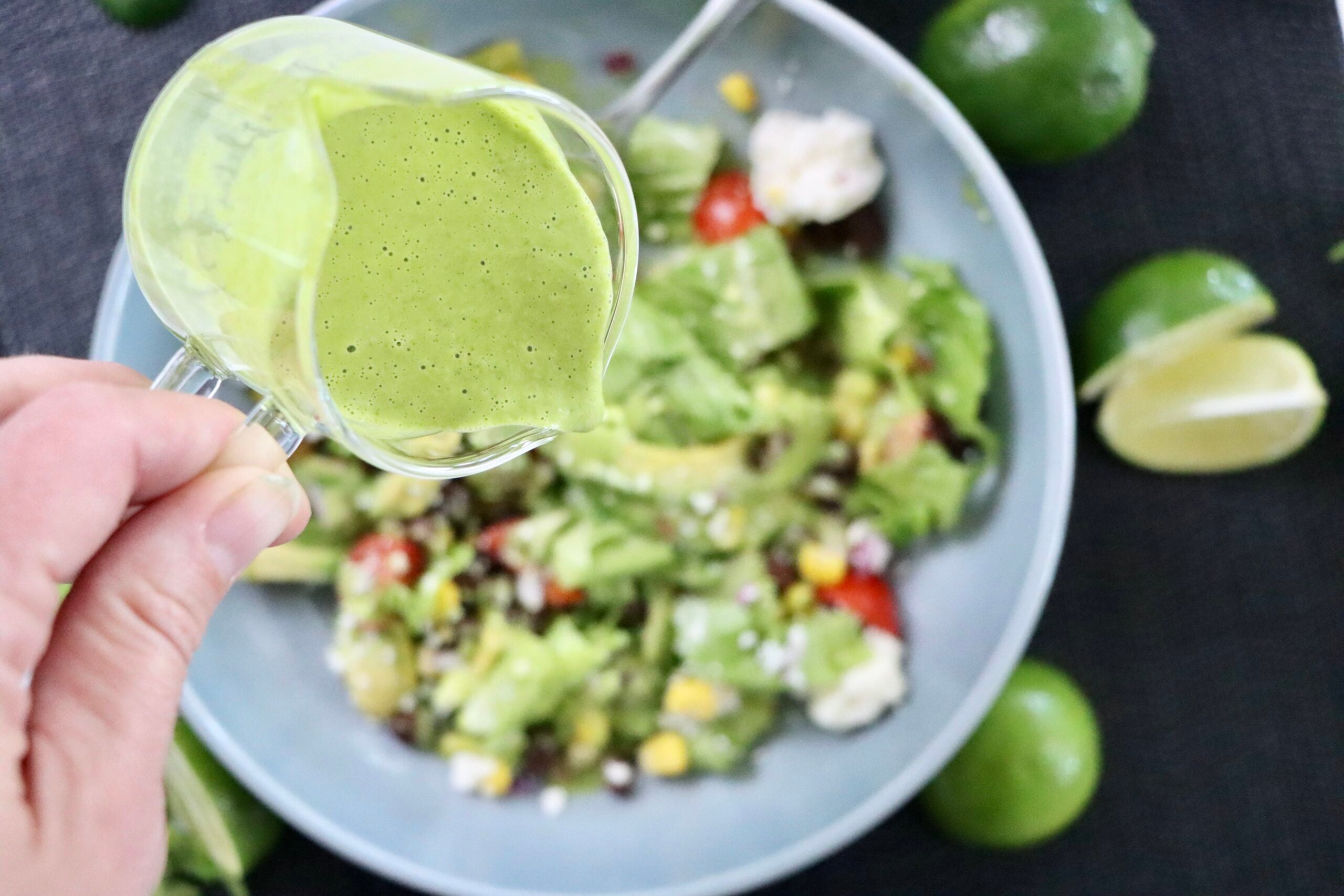 Close-up of homemade cilantro lime dressing being poured over a salad.