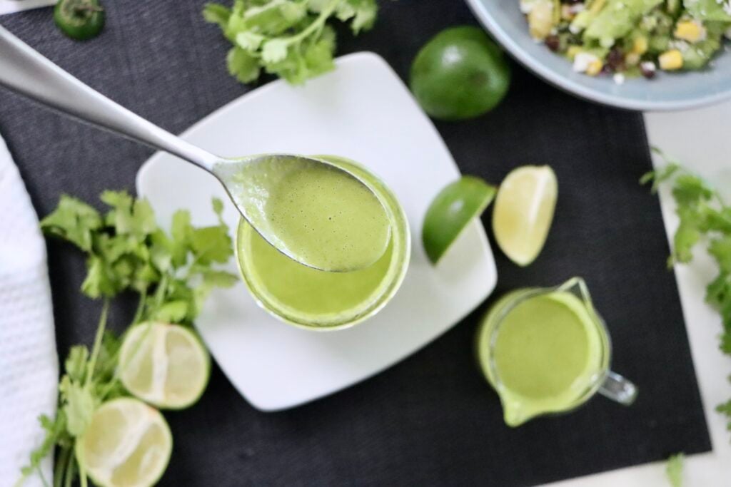Close-up of vibrant green cilantro lime dressing with a creamy consistency in a small bowl.