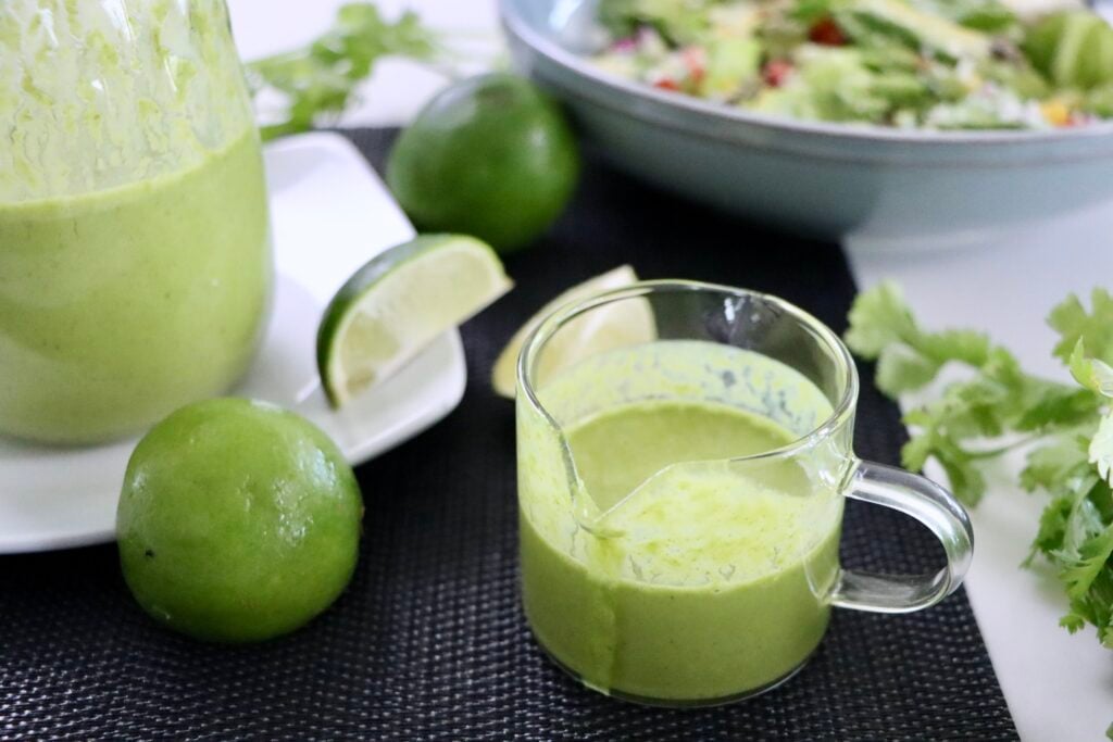 Blender-made cilantro lime salad dressing with visible fresh herbs in a smooth creamy texture.