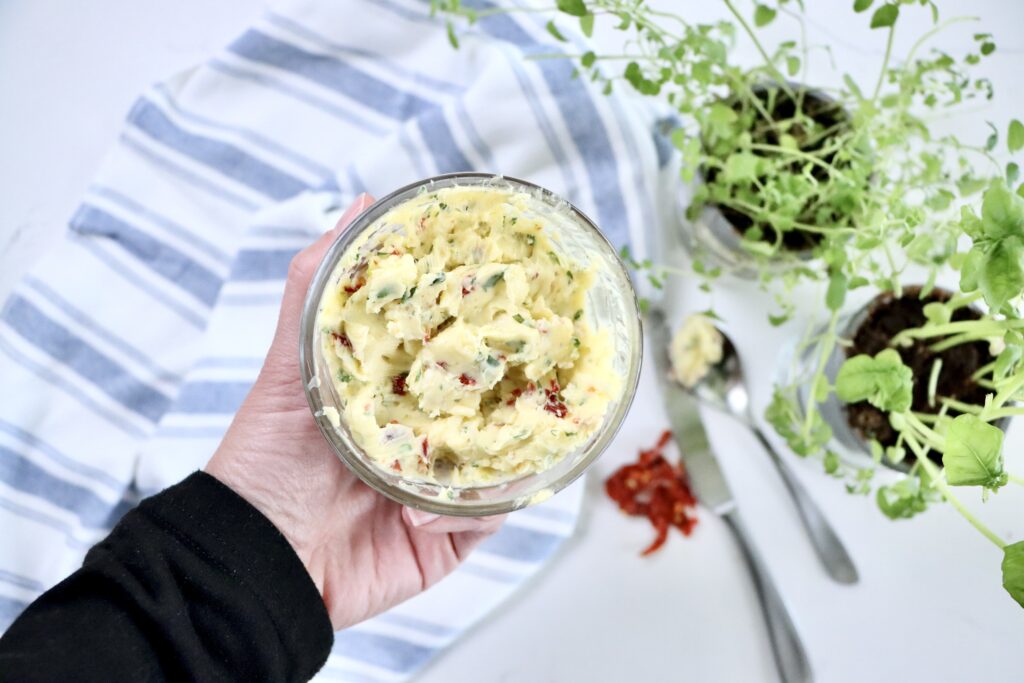 Close-up of gourmet compound butter made from real ingredients including garlic, basil, oregano, brie, and sun-dried tomatoes.