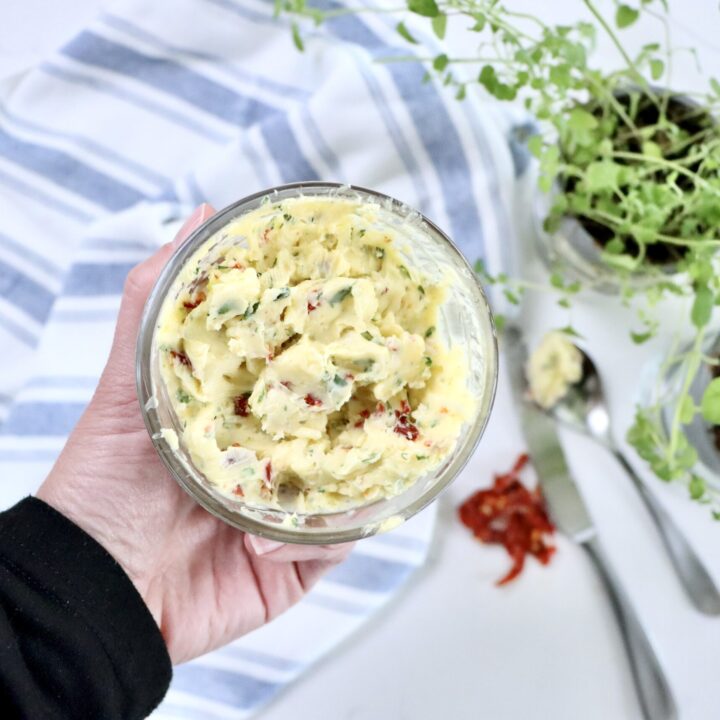 Close-up of gourmet compound butter made from real ingredients including garlic, basil, oregano, brie, and sun-dried tomatoes.