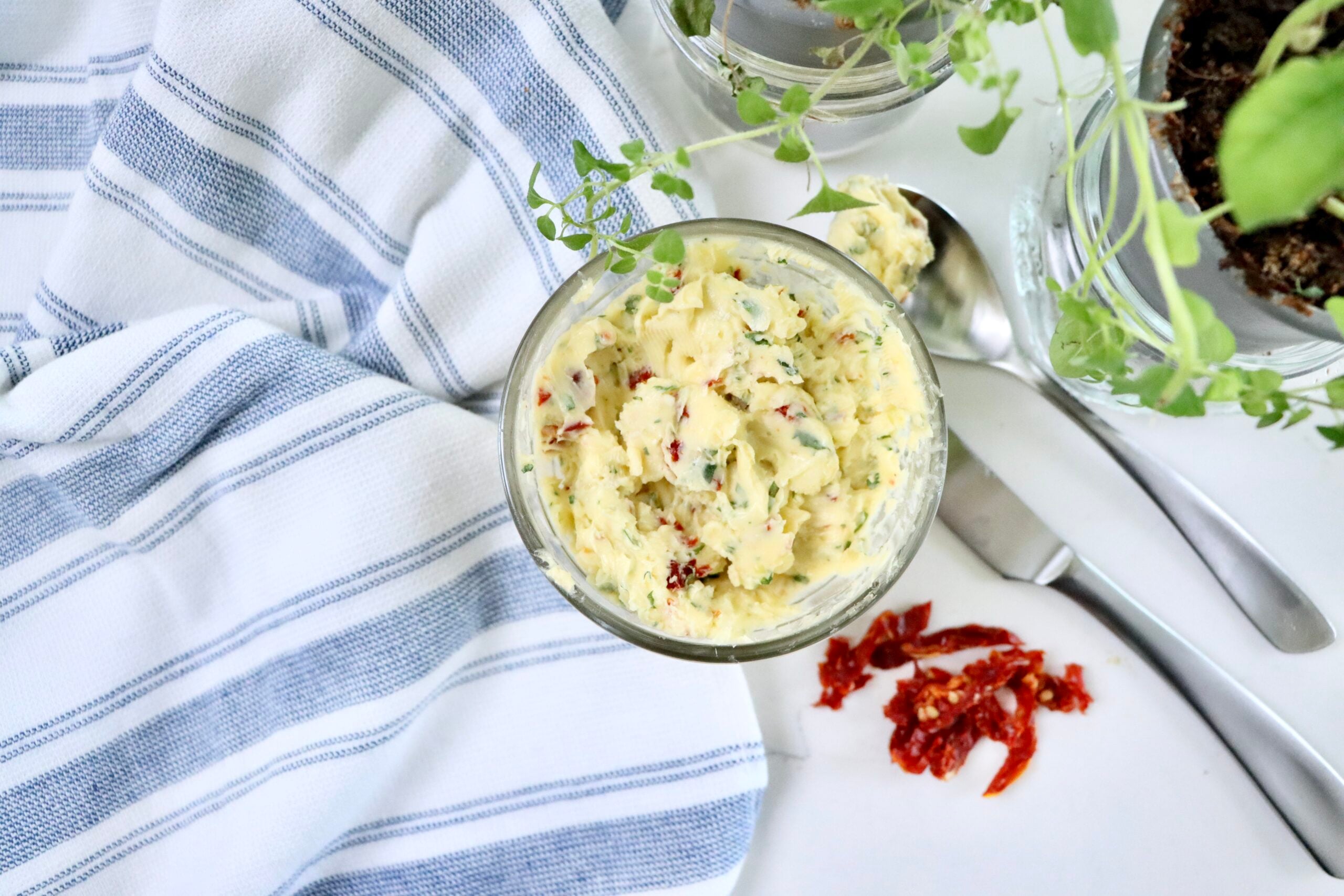 Close-up of gourmet compound butter made from real ingredients including garlic, basil, oregano, brie, and sun-dried tomatoes.