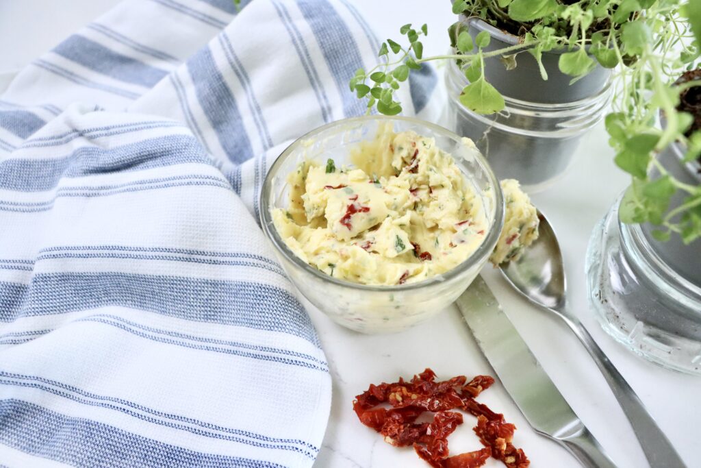 Close-up of gourmet compound butter made from real ingredients including garlic, basil, oregano, brie, and sun-dried tomatoes.