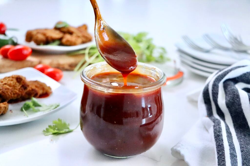 Easy homemade BBQ sauce served in a glass jar, rich in color and texture, ideal for grilled meats and sandwiches.