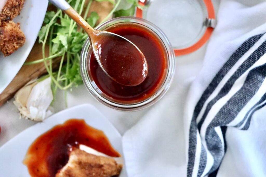 Homemade BBQ sauce in a glass jar made from ketchup, brown sugar, honey, and spices, ready to serve for grilling and dipping.