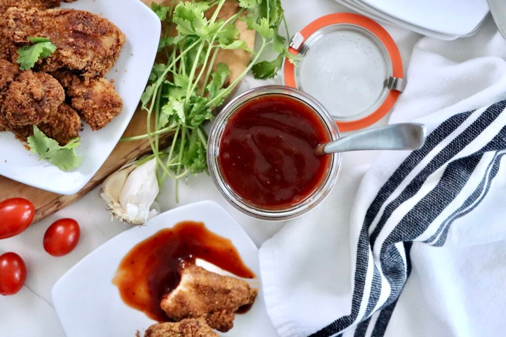 Thick and glossy homemade BBQ sauce in a jar, perfect for burgers, chicken, ribs, and summer grilling recipes.
