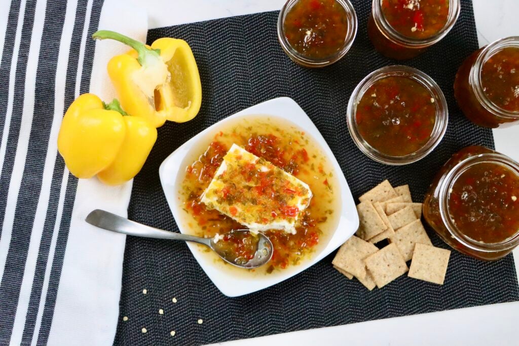 Homemade jalapeño jelly in glass jars made with fresh jalapeños, red and yellow bell peppers, sugar, and vinegar, finished with a glossy sweet and spicy texture.