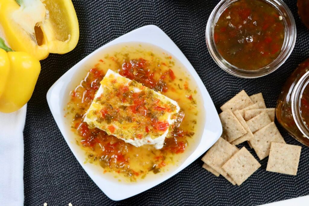 Jalapeño jelly spooned over cream cheese and served with crackers, creating a sweet and spicy appetizer spread.