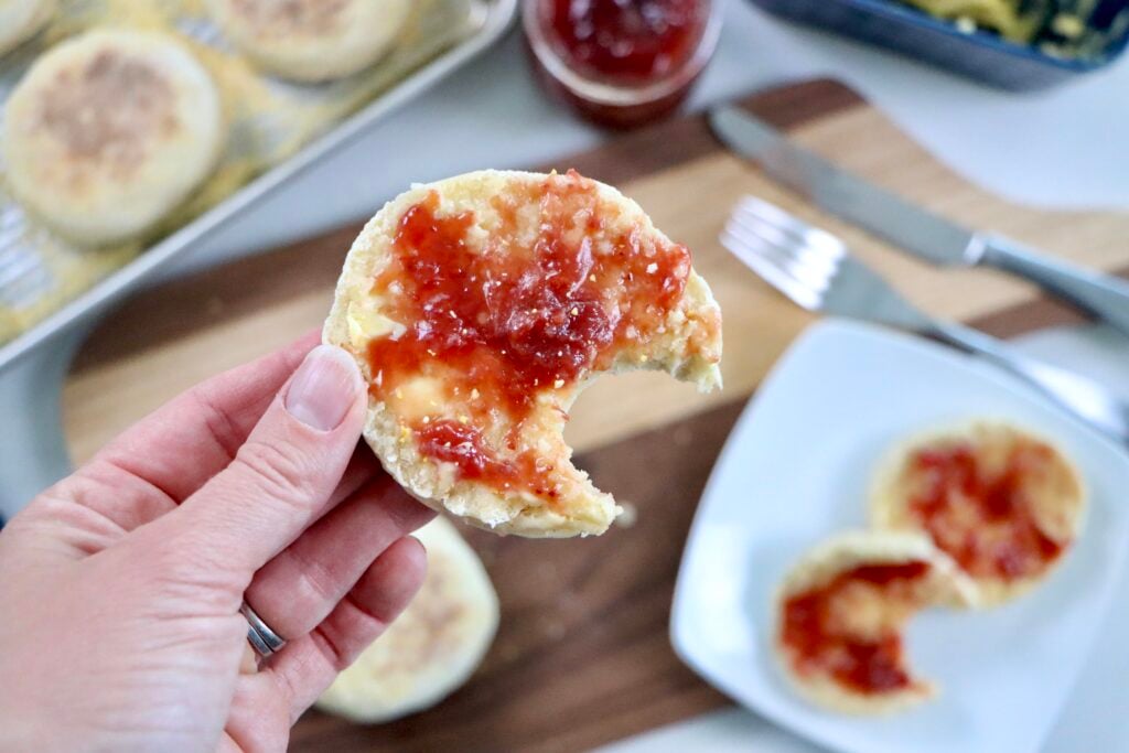 Homemade English muffins made with sourdough discard served warm with melted butter and jam on top.