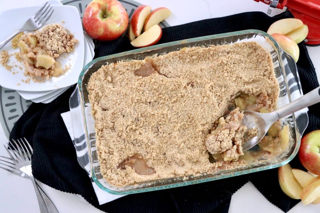 Overhead shot of homemade apple crisp with sliced baked apples visible beneath a crumbly cinnamon topping