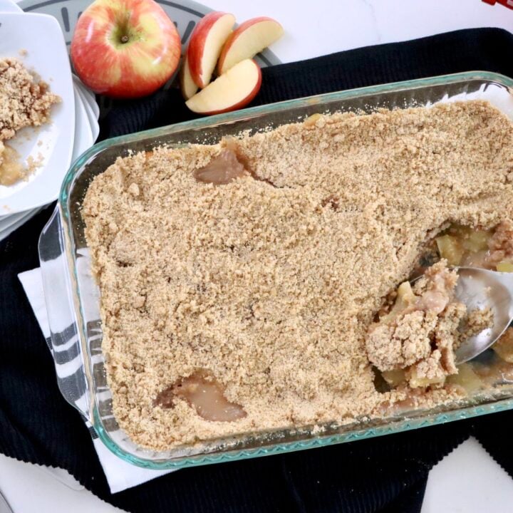 Overhead shot of homemade apple crisp with sliced baked apples visible beneath a crumbly cinnamon topping