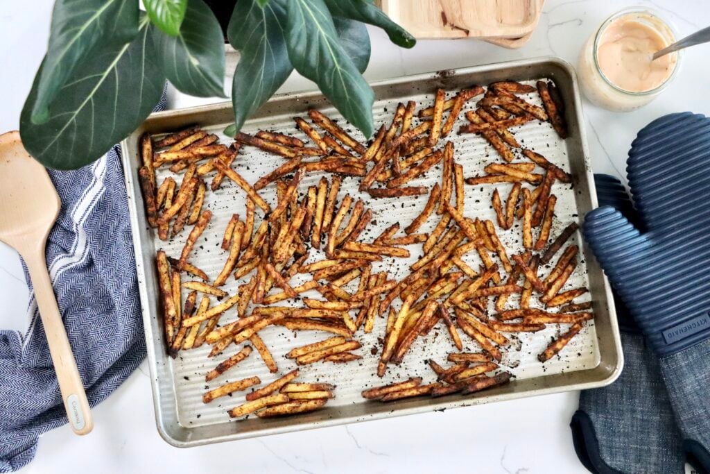 Crispy golden oven-baked fries seasoned with paprika and garlic on a baking sheet