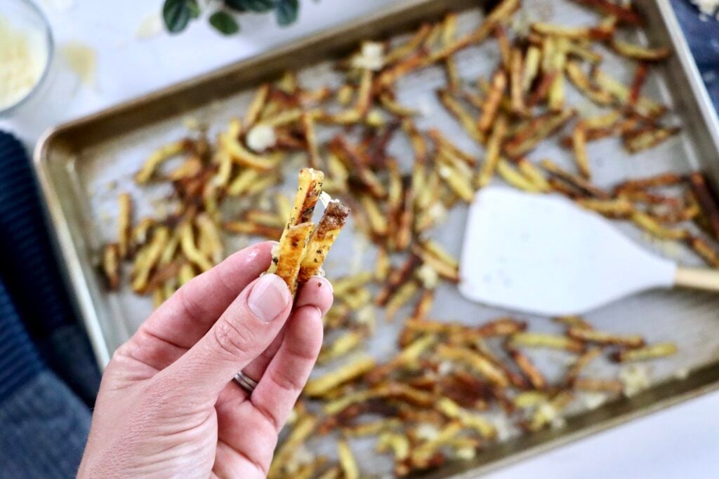 Close-up texture shot of crispy fry edges coated in melted parmesan and garlic